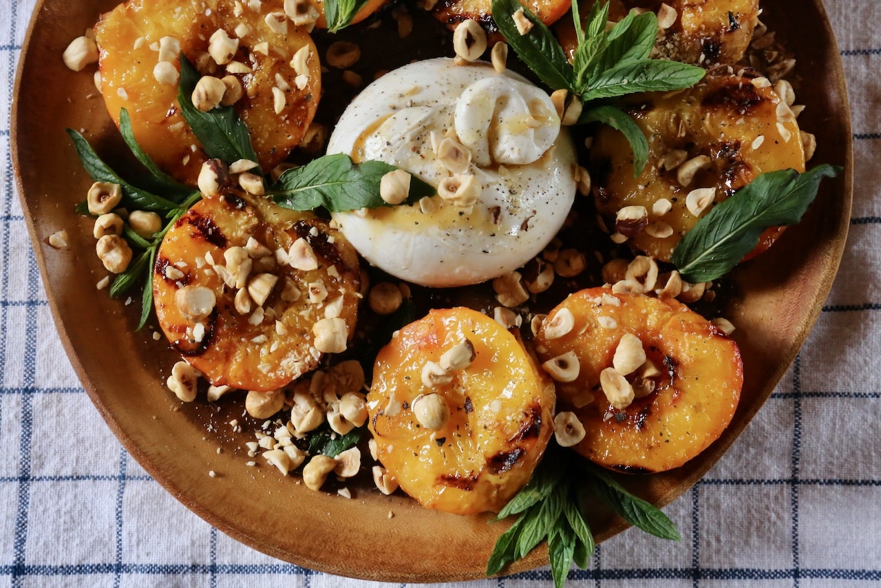Garnish this Grilled Peach and Burrata Salad recipe with roasted hazelnuts and fresh mint. 