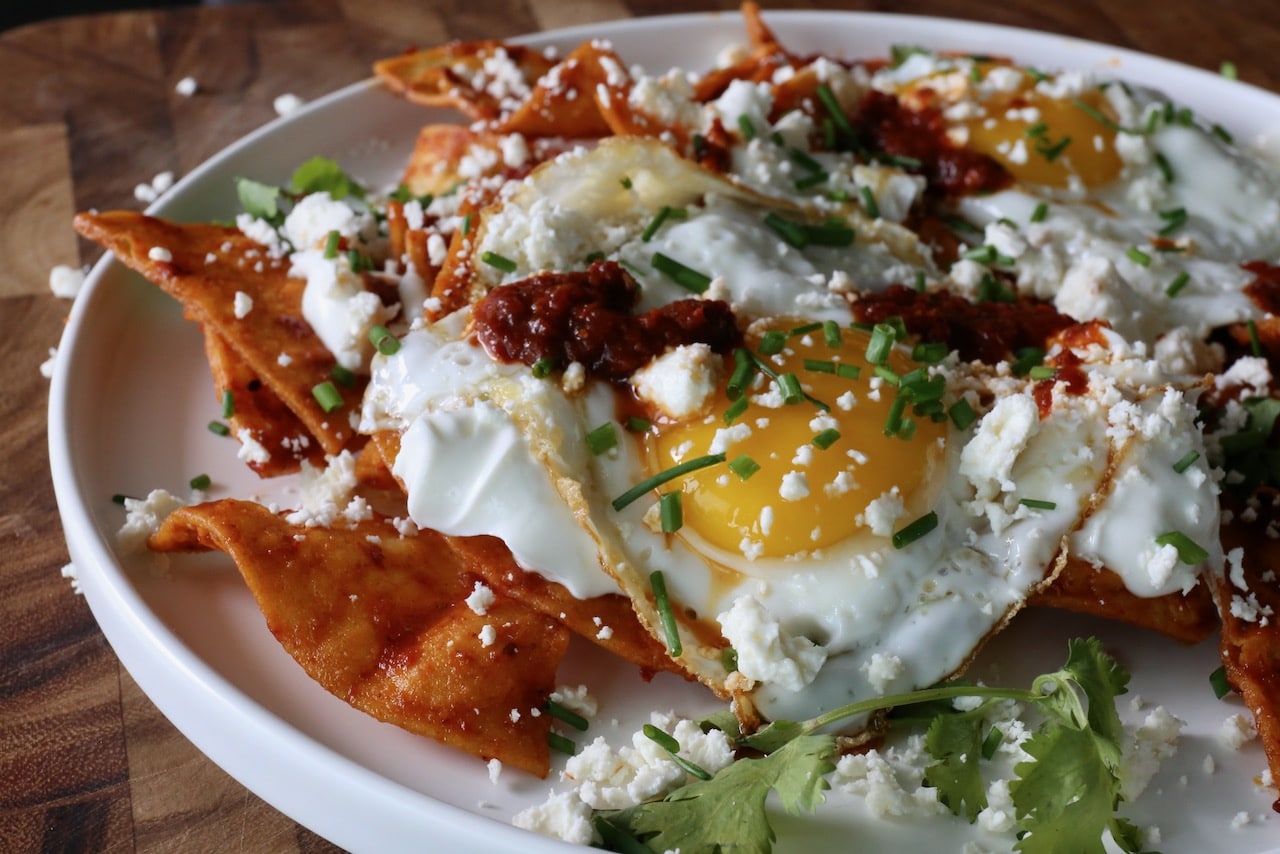 Garnish the popular Mexican breakfast with crumbled feta, chile sauce and chopped scallions. 