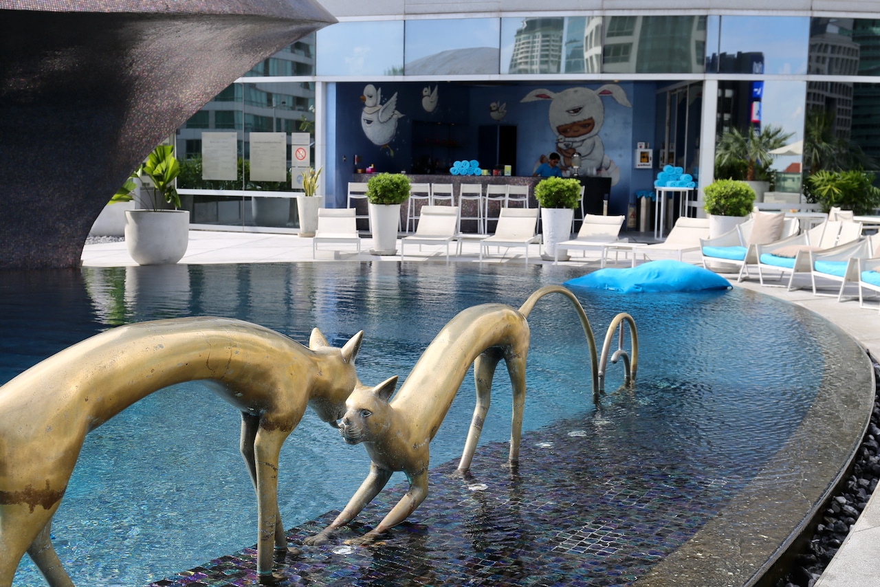 Two feline sculptures kiss at the W Bangkok Hotel's cat eye-shaped rooftop swimming pool.