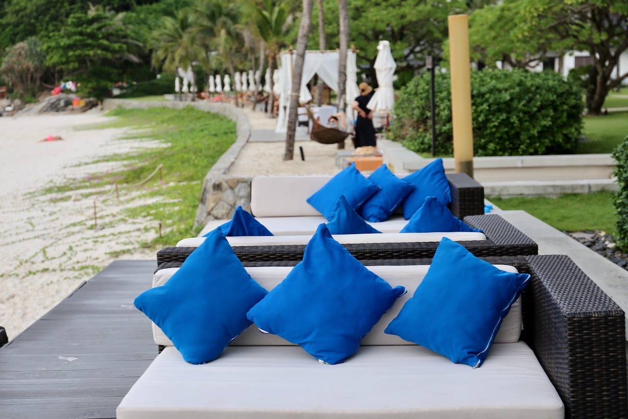 Comfy sofas sit perched over The Racha Resort's soft sandy beach at Lobby Bar.